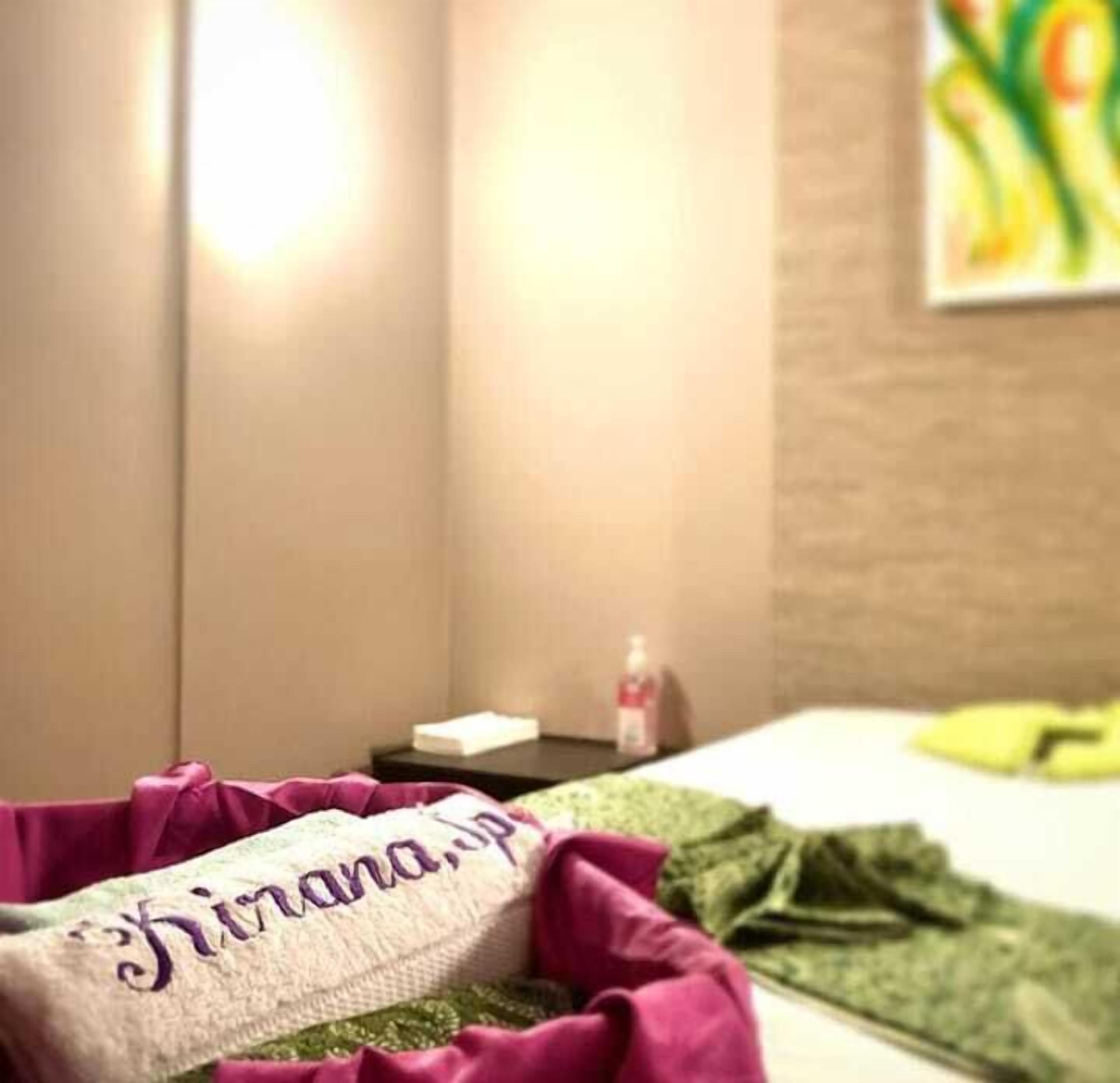 Een hotelkamer met een bed, een klein tafeltje met een fles en een schilderij aan de muur.