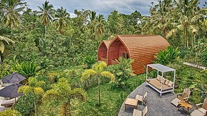 A wooden structure with a curved roof surrounded by lush greenery and palm trees. - Antagana Retreat (Selemadeg)