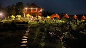 A well-lit building with a staircase leading to a covered entrance, surrounded by palm trees and a pathway. - Antagana Retreat (Selemadeg)