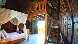 A wooden cabin with a bed under a canopy, a staircase, and a view of the outside. - Antagana Retreat (Selemadeg)