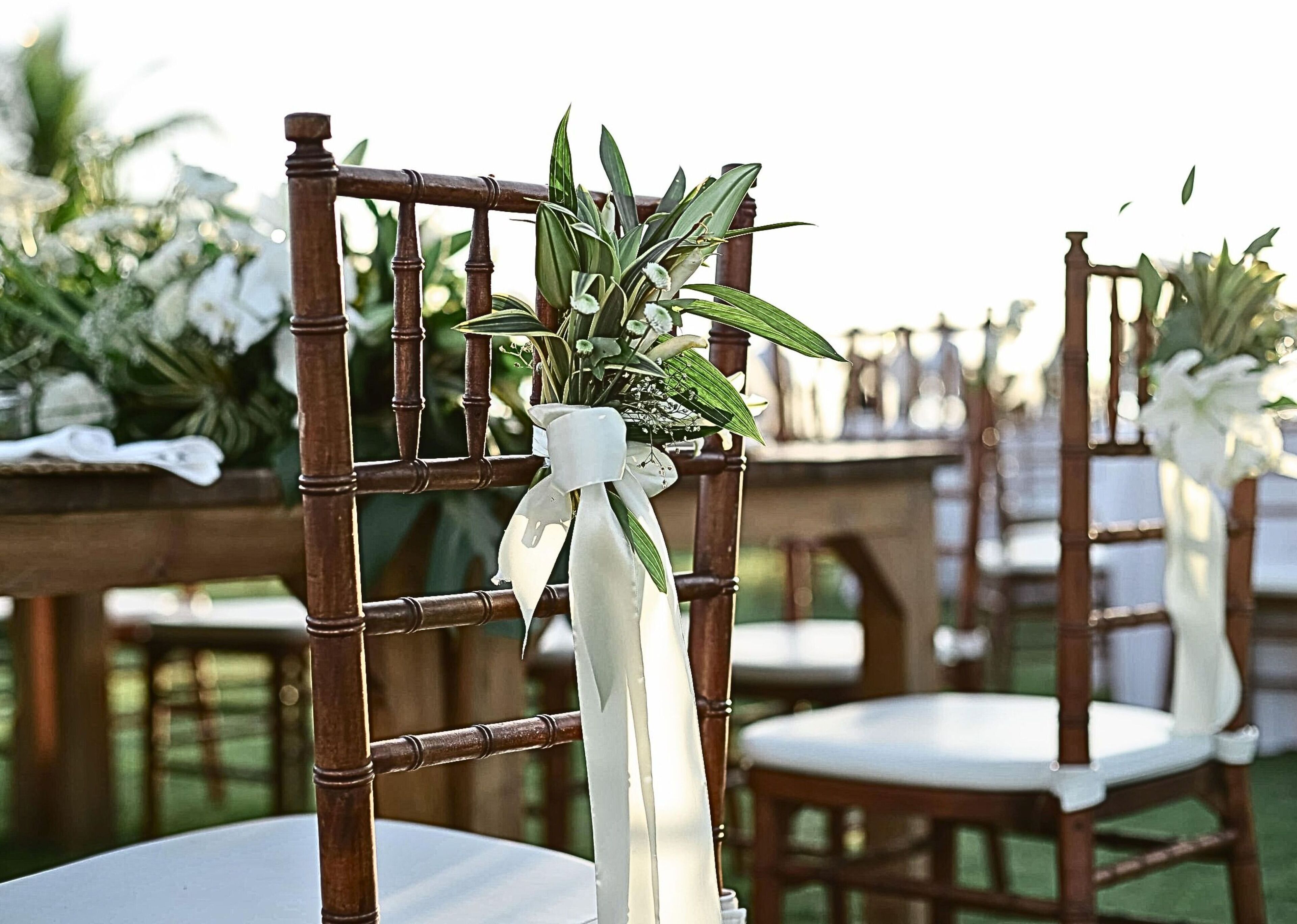 A chair with a white ribbon and a small plant arrangement.