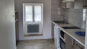 Une cuisine compacte dotée d’une fenêtre, d’appareils électroménagers intégrés et d’un dosseret carrelé.