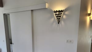 Une pièce moderne au design minimaliste, comprenant une table et deux chaises, un luminaire fixé au mur et une porte.