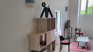 Une pièce moderne avec une bibliothèque en bois, un bureau et une chaise. Une fenêtre laisse entrer la lumière naturelle et offre une vue sur la verdure environnante.