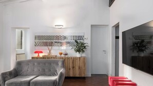 A modern living room with a grey sofa, a wooden sideboard, and a red bench. - Uffizi SuiteLarge and elegant renovated apartment in the heart of Florence (Firenze)