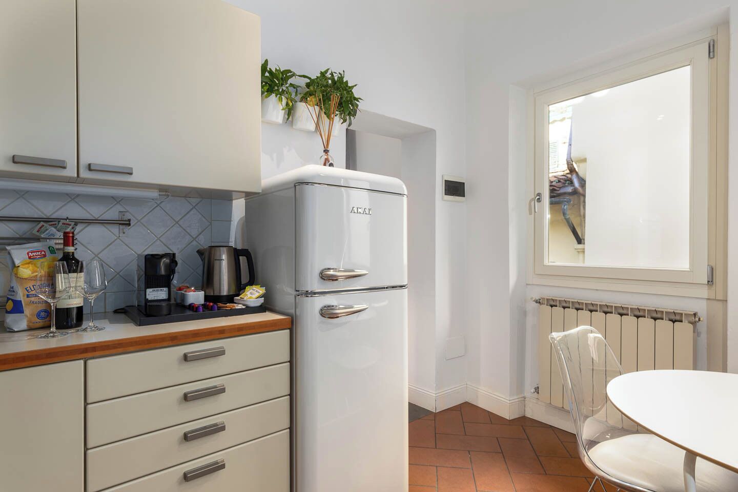 A compact kitchen with a white refrigerator, a coffee maker, and a window with a view of the outside.