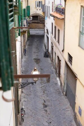 Una estrecha calle adoquinada flanqueada por edificios con balcones y contraventanas.
