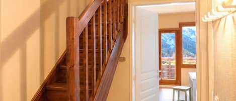 Una escalera de madera conduce a una habitación con vistas a las montañas a través de una puerta.