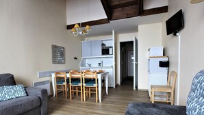 A compact living space with a kitchenette, a dining area, and a sofa.