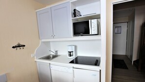 A compact kitchenette with a microwave, coffee maker, and dishwasher.
