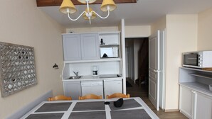 A compact kitchen with a dining table, chairs, and a microwave.