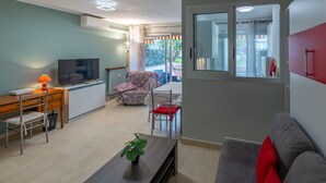 A living room with a sofa, a TV, a desk, and a chair. - Air-conditioned studio, quiet, Menton center, terrace (Menton)
