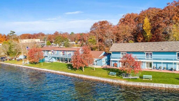A waterfront hotel with a pool, a lawn, and a view of the water.