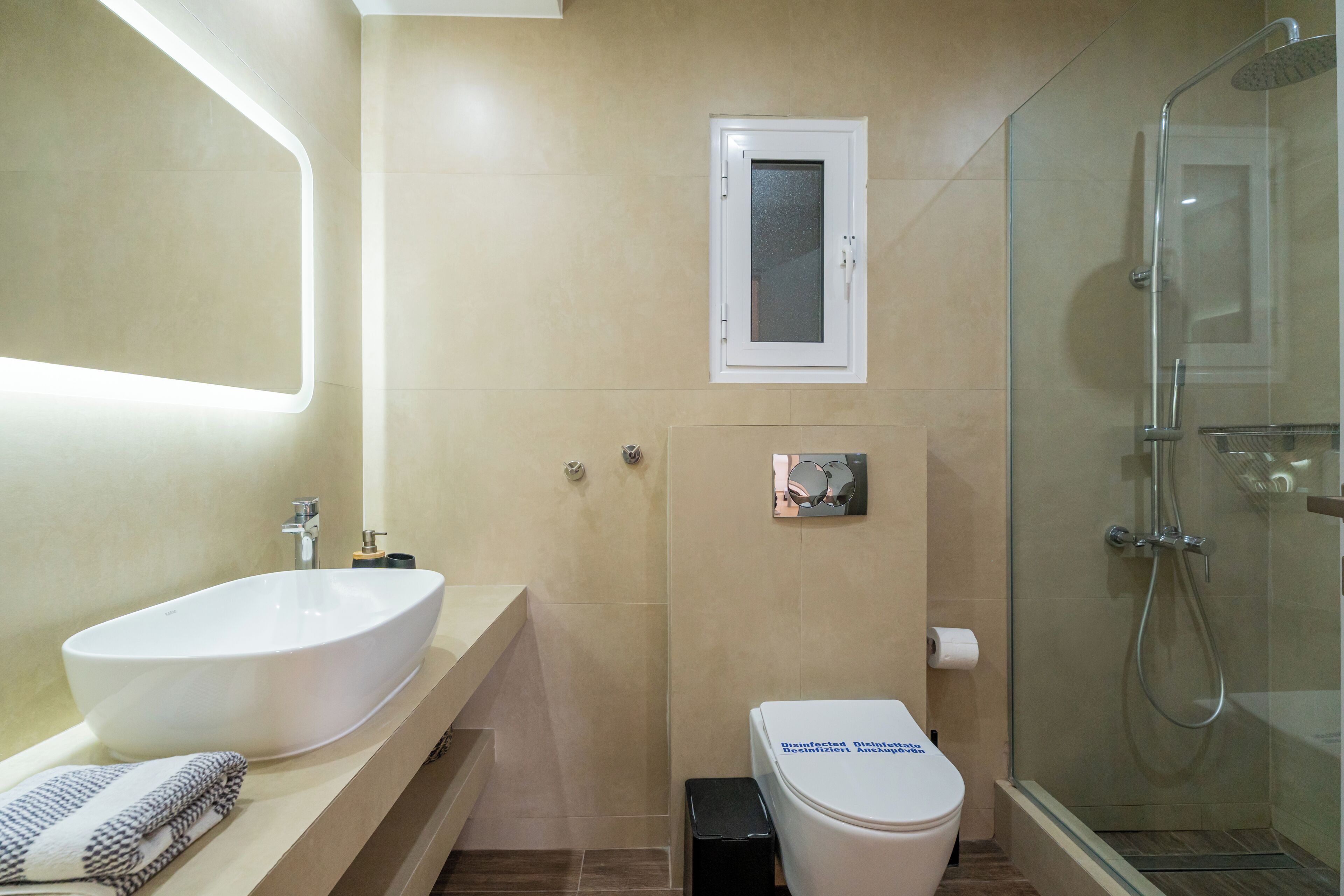 Un baño moderno con un lavamanos ovalado grande, un inodoro y una ducha con cerramiento de vidrio.