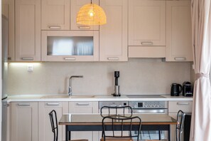 A modern kitchen with a microwave, stove, coffee maker, and a hanging light fixture.