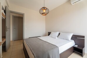 A bedroom with a bed, bedside table, and a hanging light fixture.