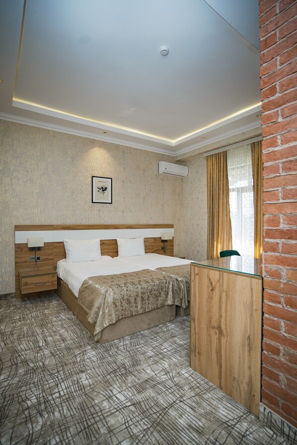 A hotel room with a large bed, bedside tables, a wooden dresser, a mirror, and a ceiling light. - Lakeside Hotel & Spa (Gabala)