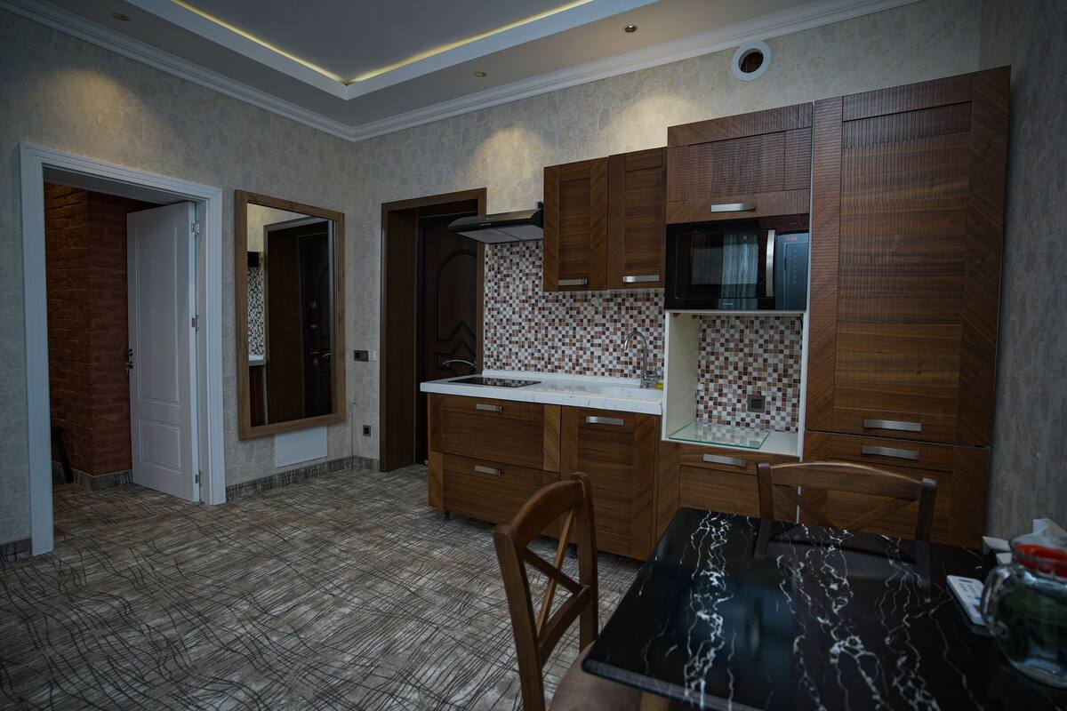 Uma cozinha moderna com armários de madeira, micro-ondas e painel de azulejos.