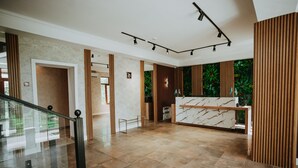 Eine großzügige Lobby mit einer Rezeption, einer Treppe und Blick auf Grünflächen.