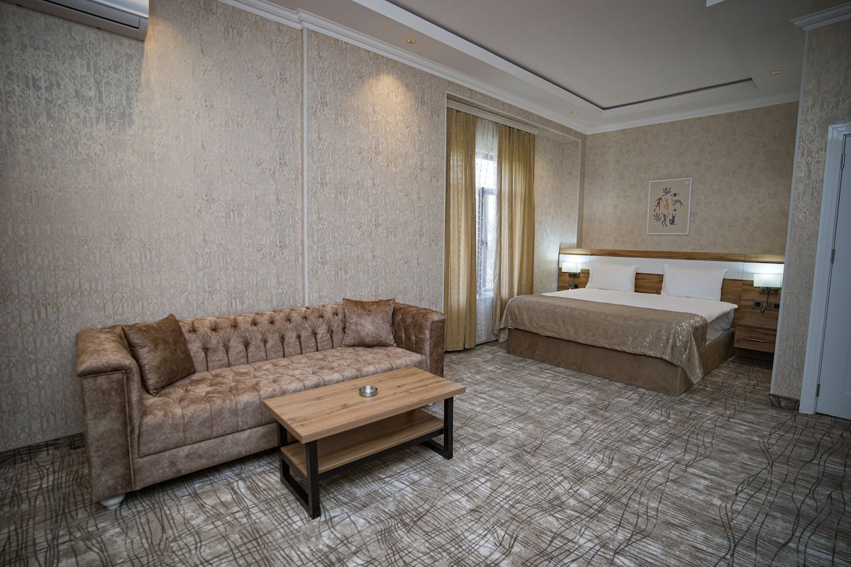 Quarto de hotel com sofá, cama, mesa de cabeceira e cabeceira.