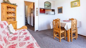 Ein gemütliches Zimmer mit einem Holzschrank, einem Esstisch mit Stühlen, einer Mikrowelle und einer kleinen Küchenzeile.