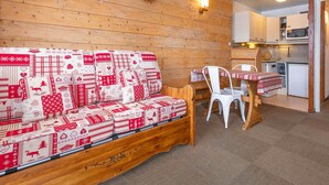 A cozy room with a wooden bench, a table with chairs, and a kitchenette in the background. - Cozy apartment for 4 in Avoriaz with southeast-facing balcony (Avoriaz)