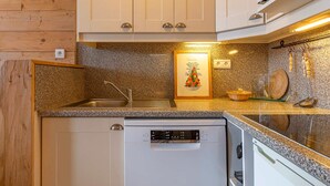 A compact kitchen with white cabinetry, a granite countertop, a dishwasher, and a microwave. - Cozy apartment for 4 in Avoriaz with southeast-facing balcony (Avoriaz)