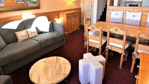 Una habitación acogedora con sofá, mesa de comedor de madera, sillas y una pequeña mesa redonda.