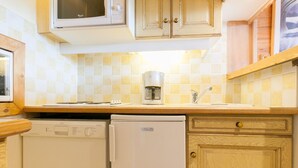 Una cocina compacta equipada con microondas, cafetera, lavavajillas y refrigerador.