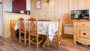 A wooden interior with a dining table, chairs, a kitchen area, and a television. - Central apartment for 6 pers, TV, WiFi, ski locker (Avoriaz)