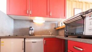 A compact kitchen with red cabinets, a dishwasher, a coffee maker, and a microwave. - Central apartment for 6 pers, TV, WiFi, ski locker (Avoriaz)