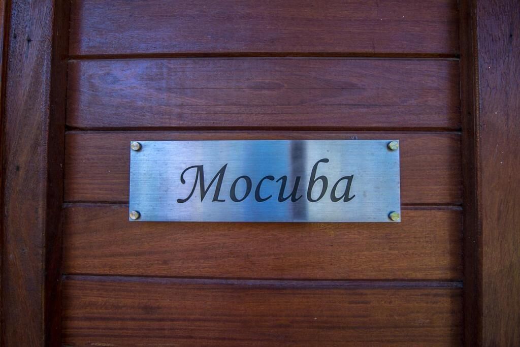 Eine Metallplakette mit der Aufschrift "Mocuba" auf einer Holztafel.