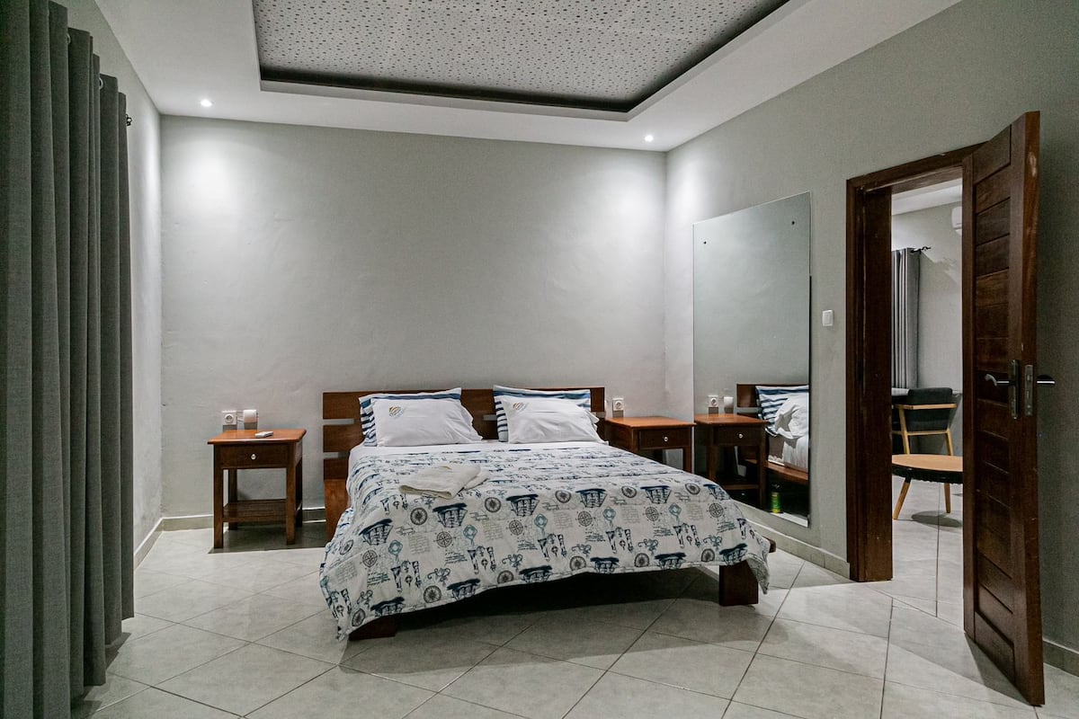 Un dormitorio con cama, dos mesitas de noche, un espejo y una puerta.