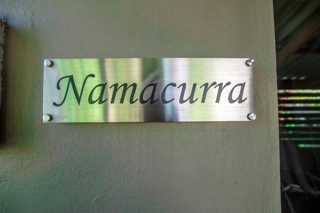 A metallic sign with the name "Namacurra" mounted on a wall.