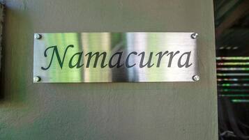 A metallic sign with the name "Namacurra" mounted on a wall.