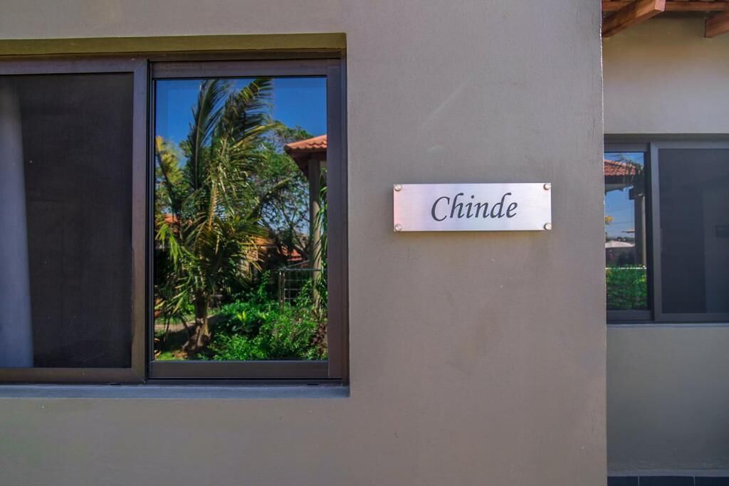 Un bâtiment sur lequel on peut lire l’inscription « Chinde », avec une fenêtre donnant sur des palmiers et une végétation luxuriante.