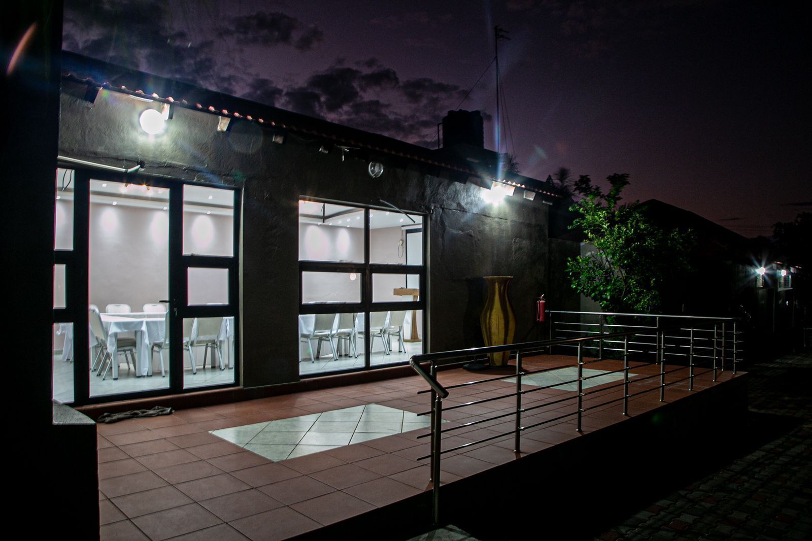 A building with large glass windows, a tiled entrance, and a metal railing.