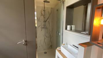 A modern bathroom with a glass-enclosed shower, a white sink, and a mirror above the sink.