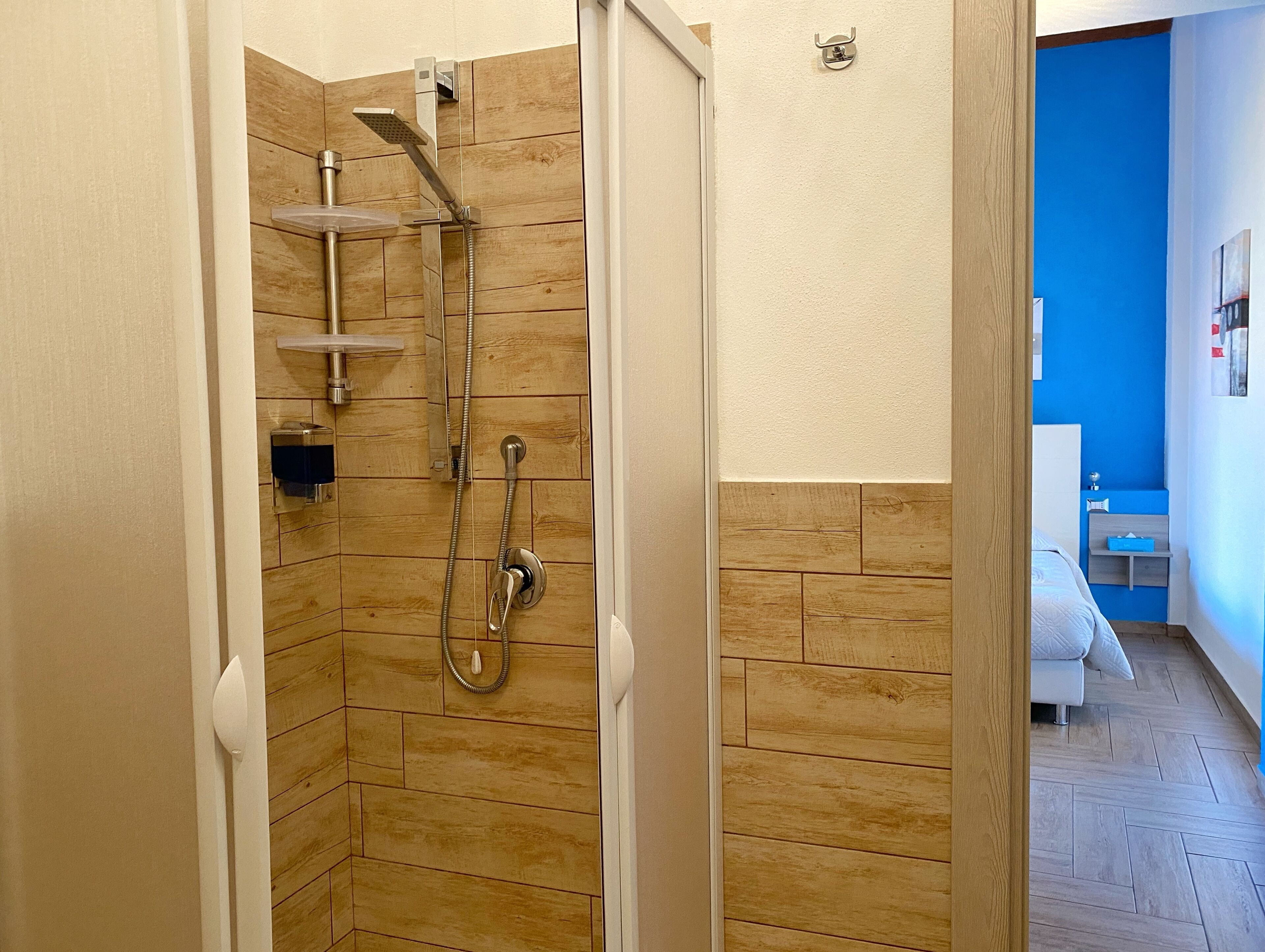 Eine Dusche mit Holzwand, einer weißen Tür und einer blauen Wand im Hintergrund.