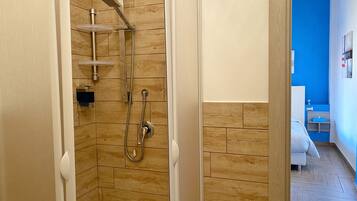 A shower with a wooden wall, a white door, and a blue wall in the background.
