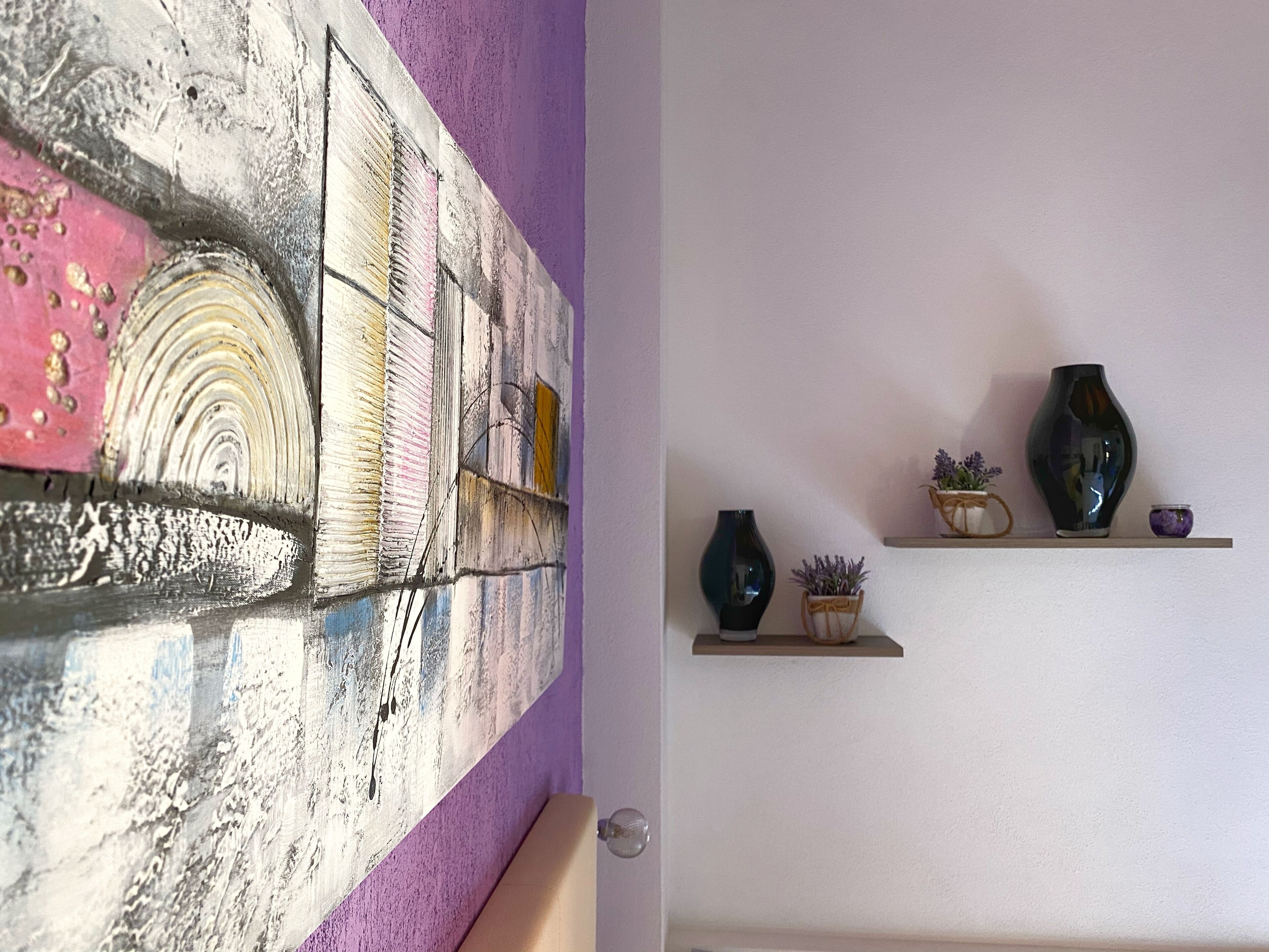 A room with a textured wall and a shelf with decorative items.