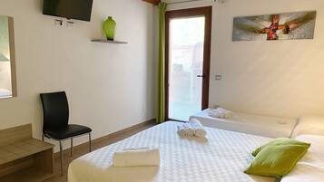 Una habitación de hotel con una cama, una silla, un televisor montado en la pared y un cuadro.