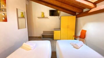 Un dormitorio con dos camas, techo de madera, un armario amarillo y una silla naranja pequeña.