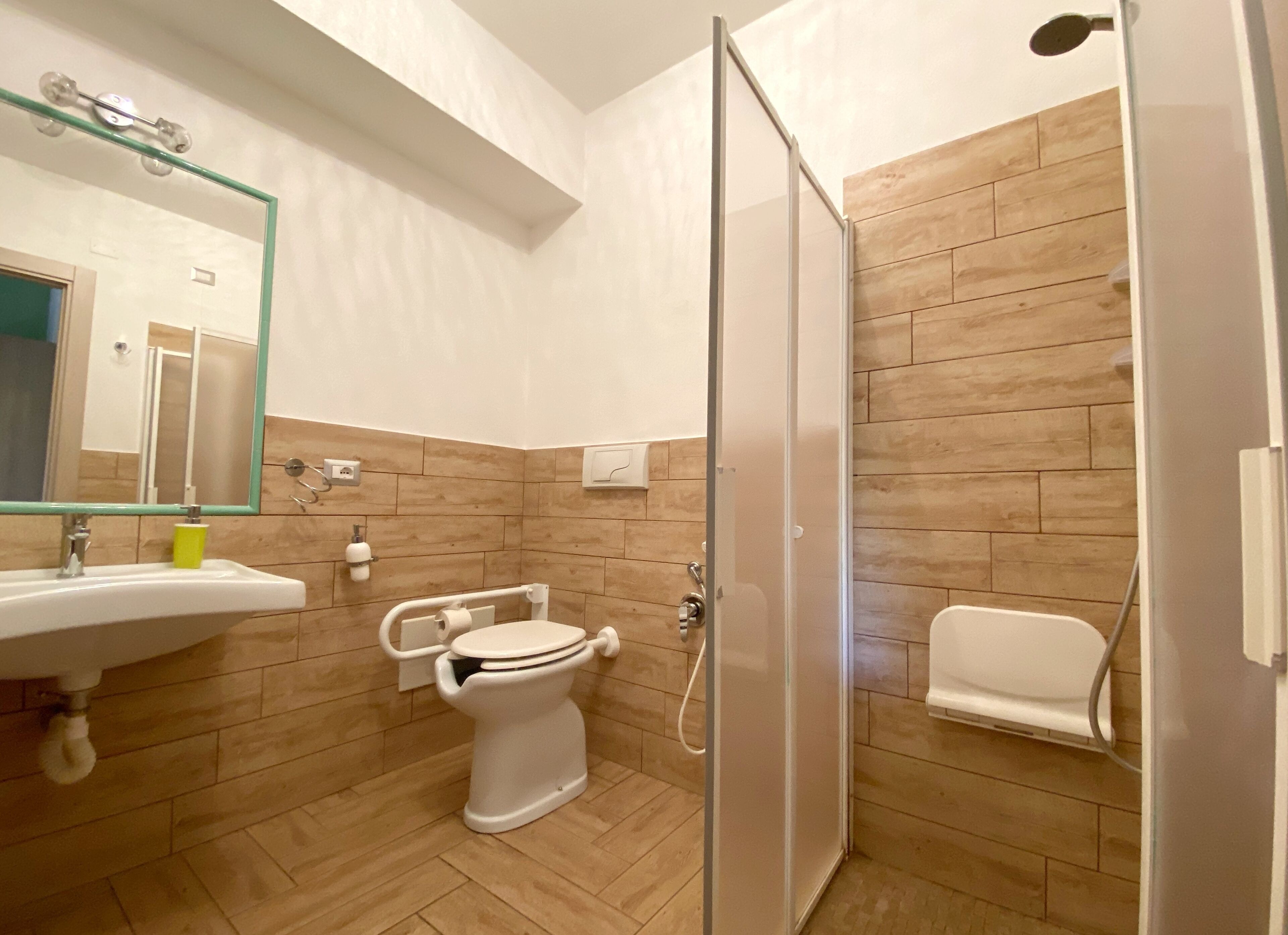 Een moderne badkamer met een douchecabine van glas, een wit wastafelmeubel en een toilet.