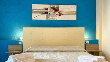 Un lit bien fait, avec une tête de lit matelassée, deux tables de chevet avec des lampes et un tableau accroché au mur.