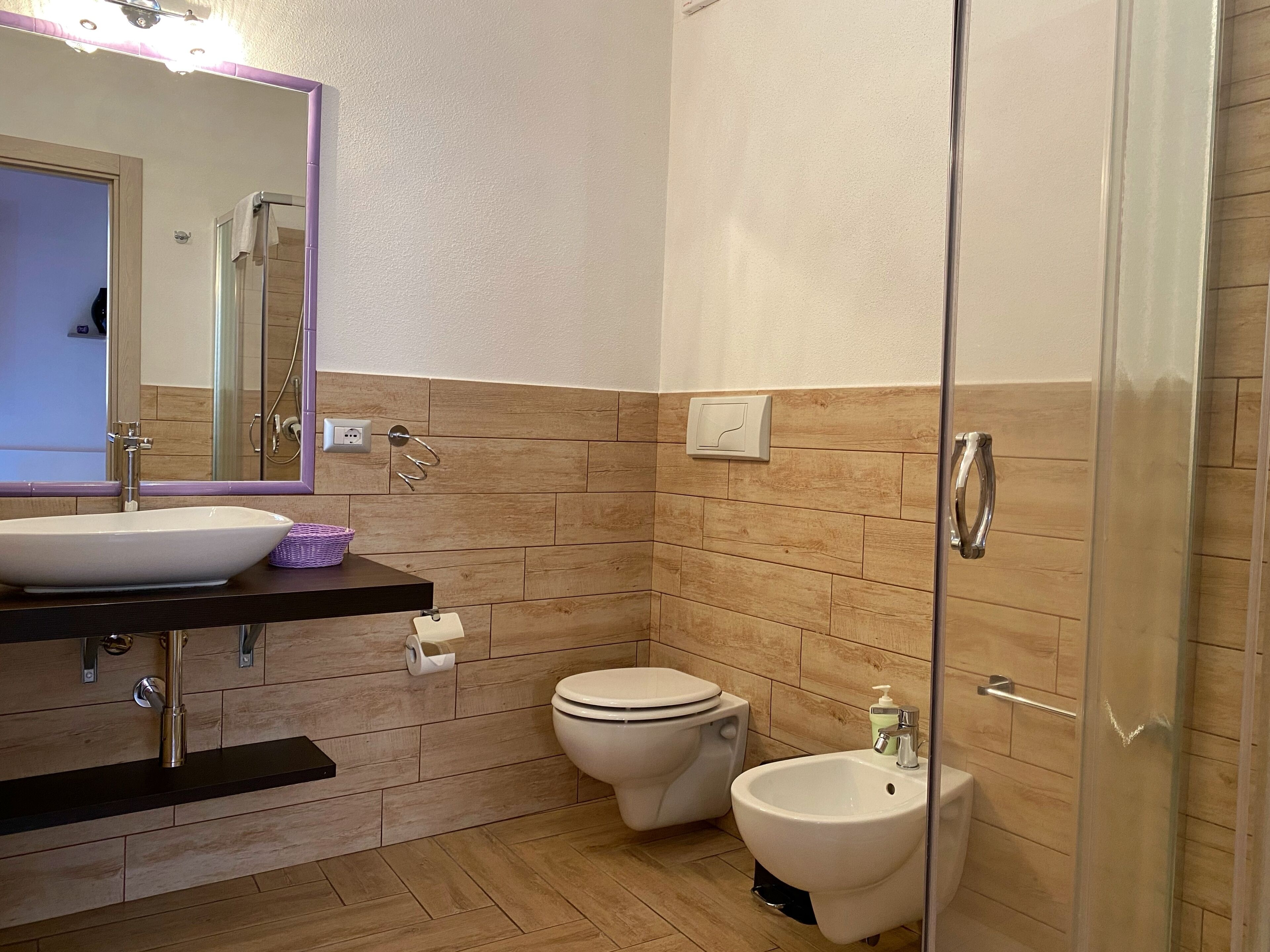 A modern bathroom with a large mirror, a sink, a toilet, and a bidet.