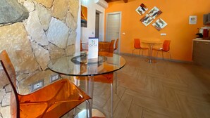 Un interior moderno con una pared de piedra, una mesa de cristal y sillas naranjas.