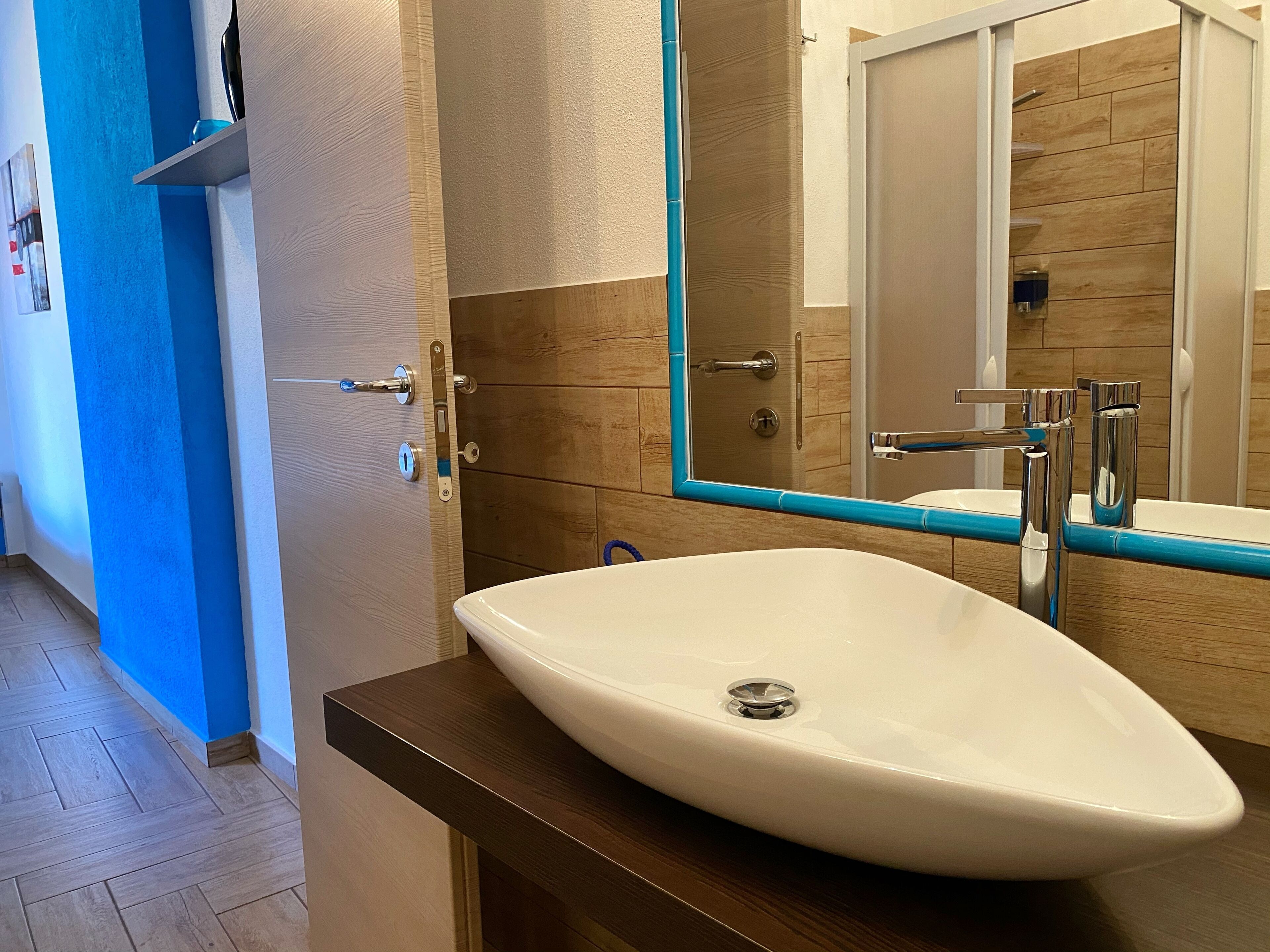 A bathroom with a white sink, a mirror, and wooden walls.