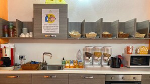 Una cocina con cafetera, microondas y varios recipientes de comida sobre la encimera.