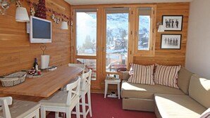 A cozy room with a wooden interior, a dining table with chairs, a sofa, and a television. - Studio for 2 with balcony in the center of Avoriaz (Avoriaz)